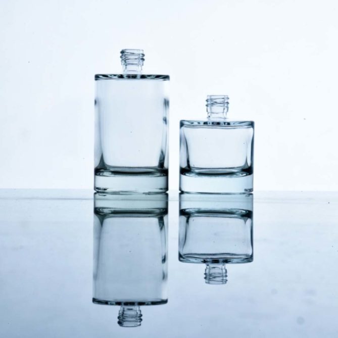 Deux flacons en verre 50 ml et 30 ml posés sur une table transparente