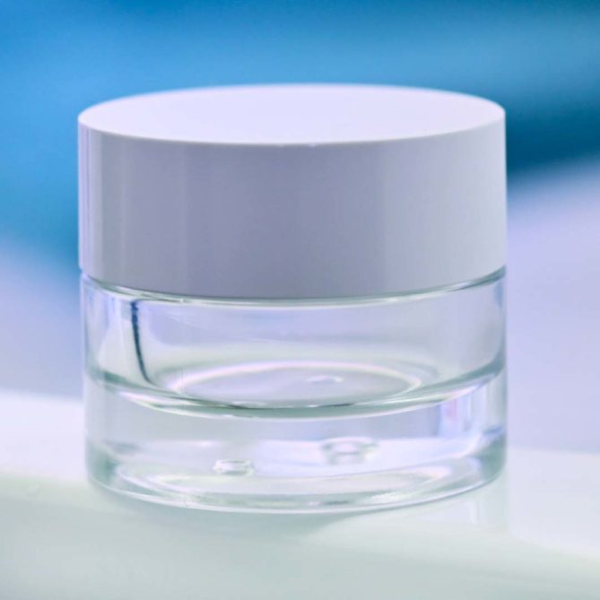 Un pot cosmétique en verre transparent avec un couvercle blanc