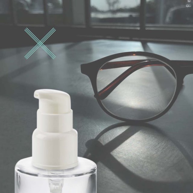 Un flacon cosmétique en verre avec une pompe posé sur un bureau avec des lunettes